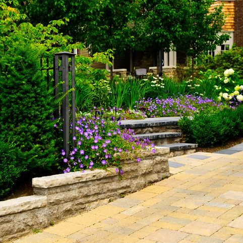 Natural stone landscaping in front of a house with lush green garden